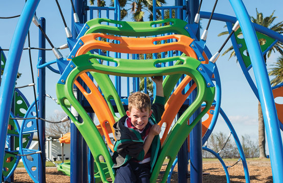 young boy playing on on park equipment